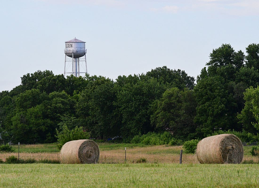 Holden, MO - Haybales on a Farm in Rural Holden Missouri with a Water Tower in the Distance Next to Green Trees